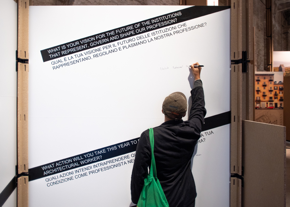 Person writing on a board with a question as a prompt: what is your vision for the future of the institutions that represent, govern, and shape our profession?